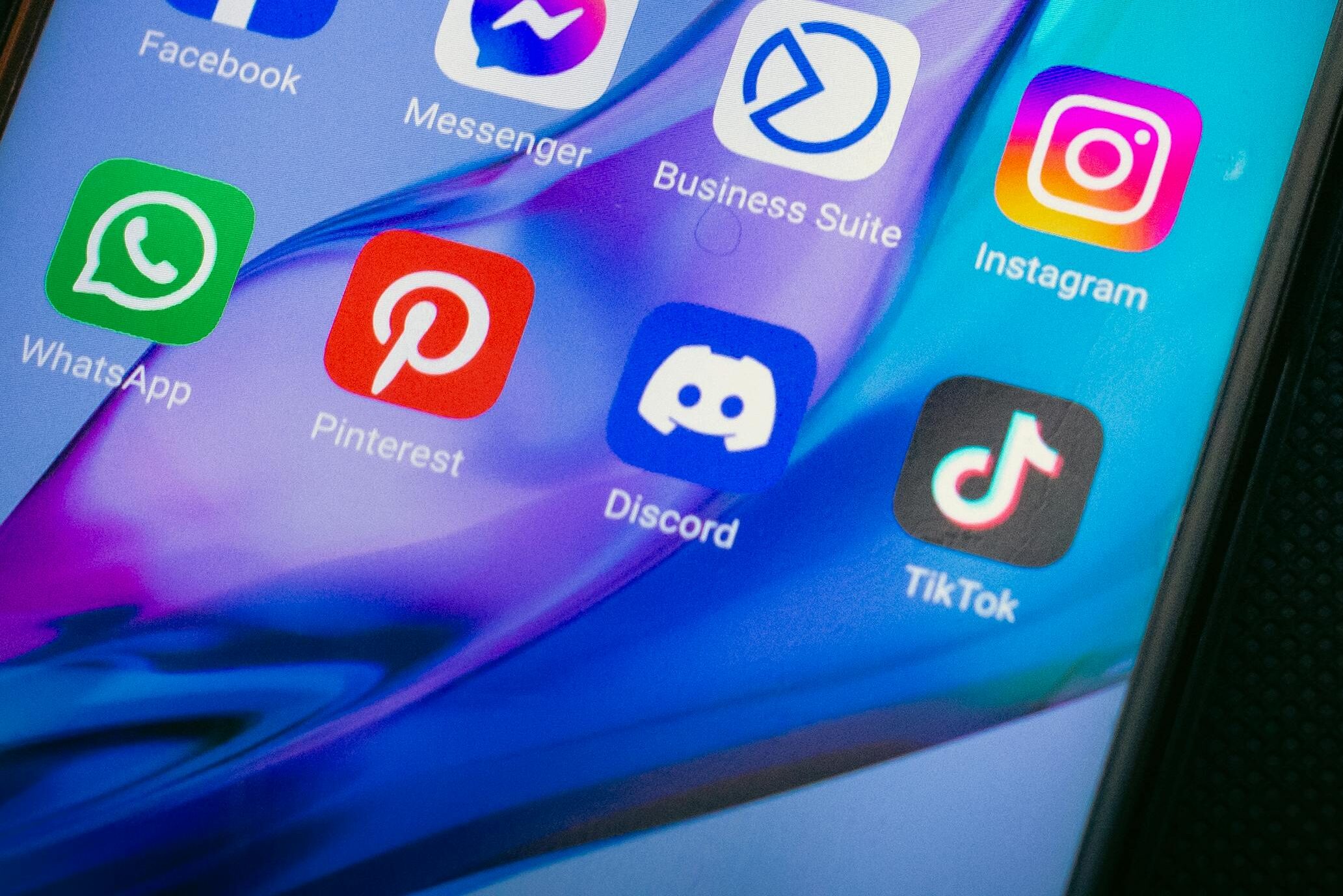 Close-up of a smartphone screen showing popular app icons like YouTube, Maps, and TikTok on a black background.